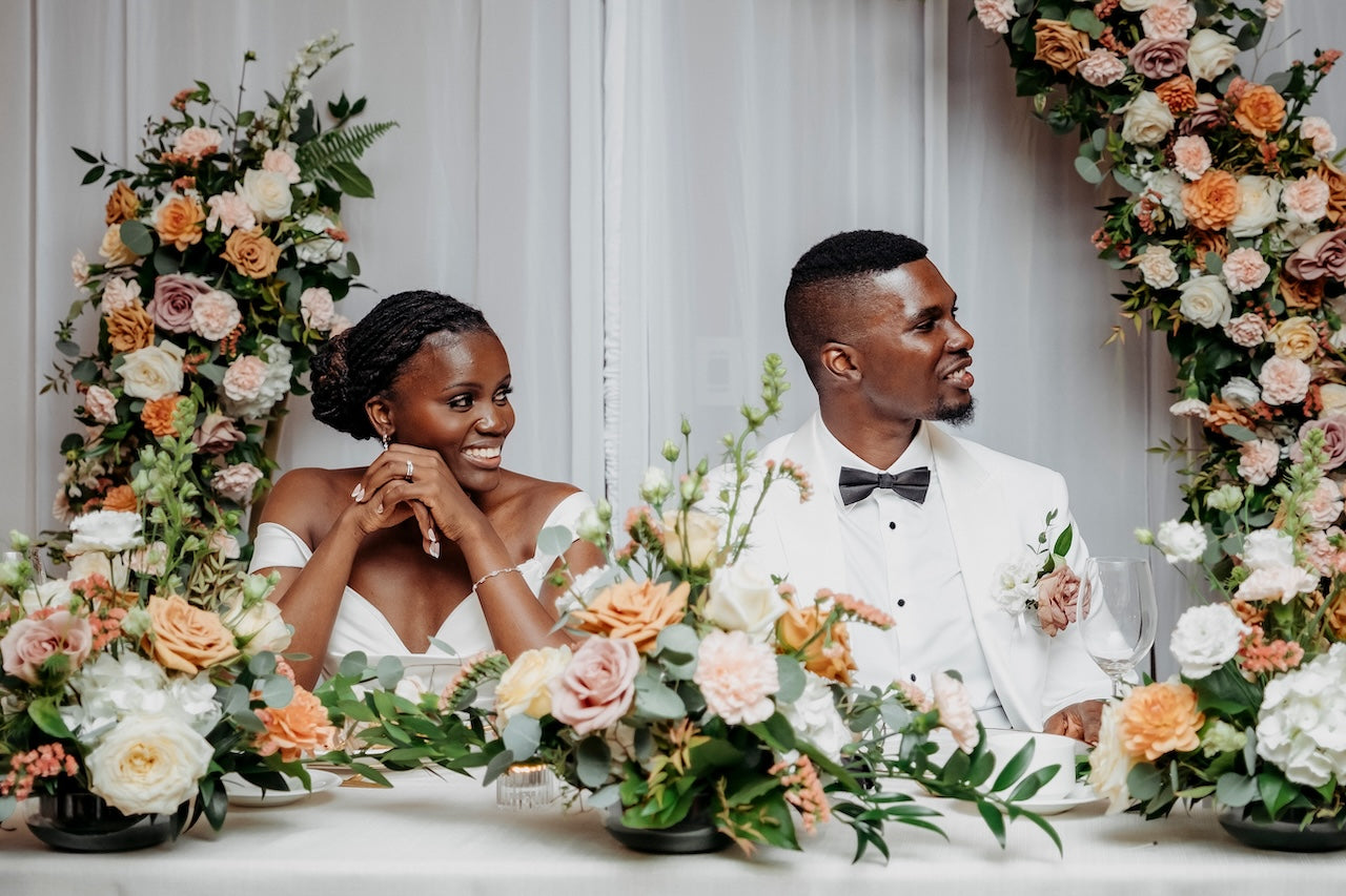 Vancouver couple sitting at a decorated wedding head table with floral arrangements at TCC.