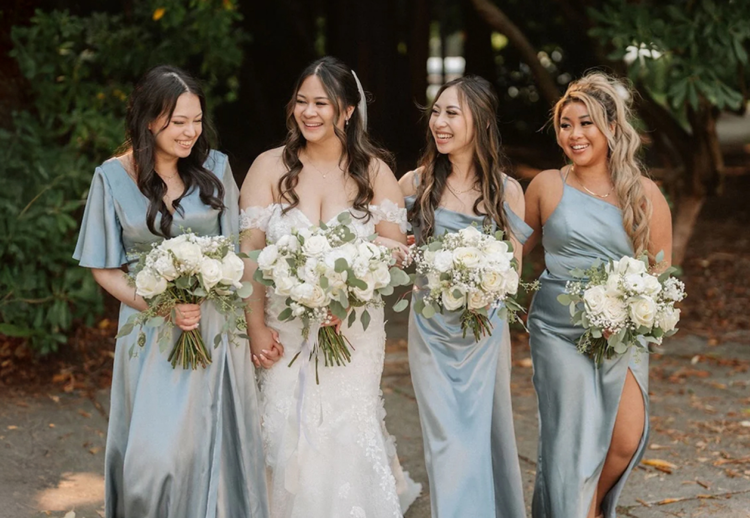 A bride with 3 bridesmaids holding white flower bouquets create by Burst Flowers Vancouver