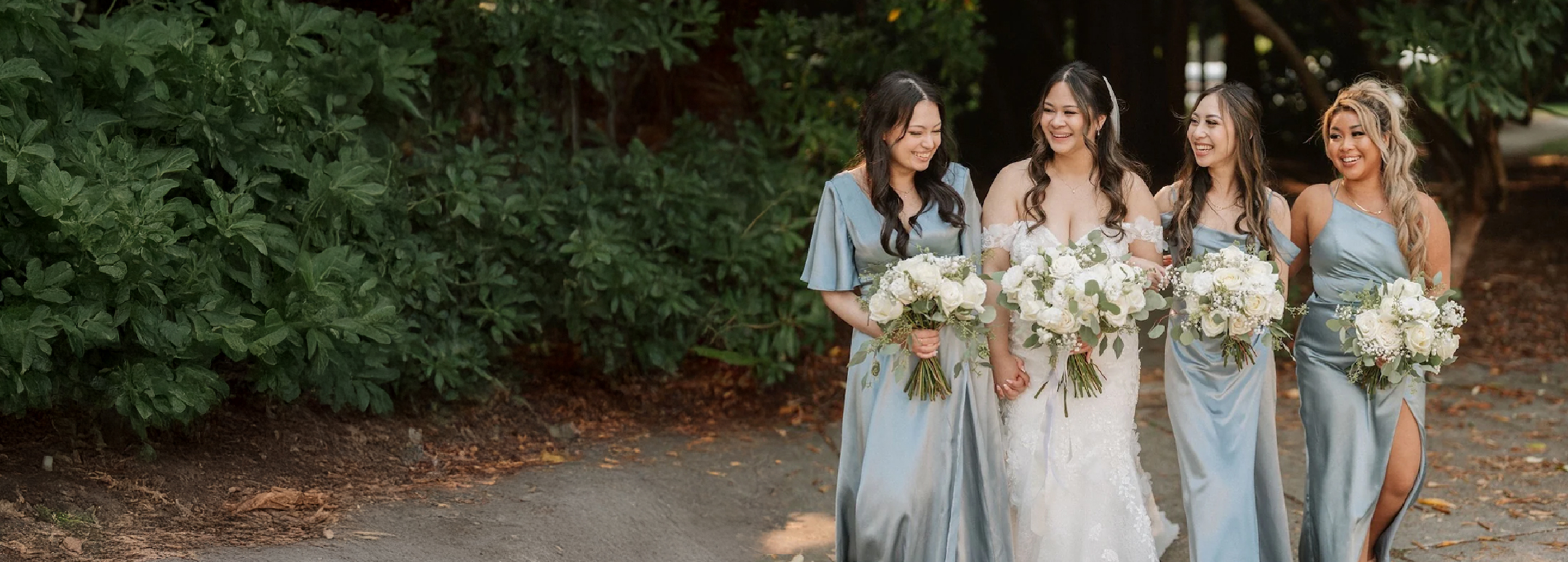 A bride with 3 bridesmaids holding white flower bouquets create by Burst Flowers Vancouver