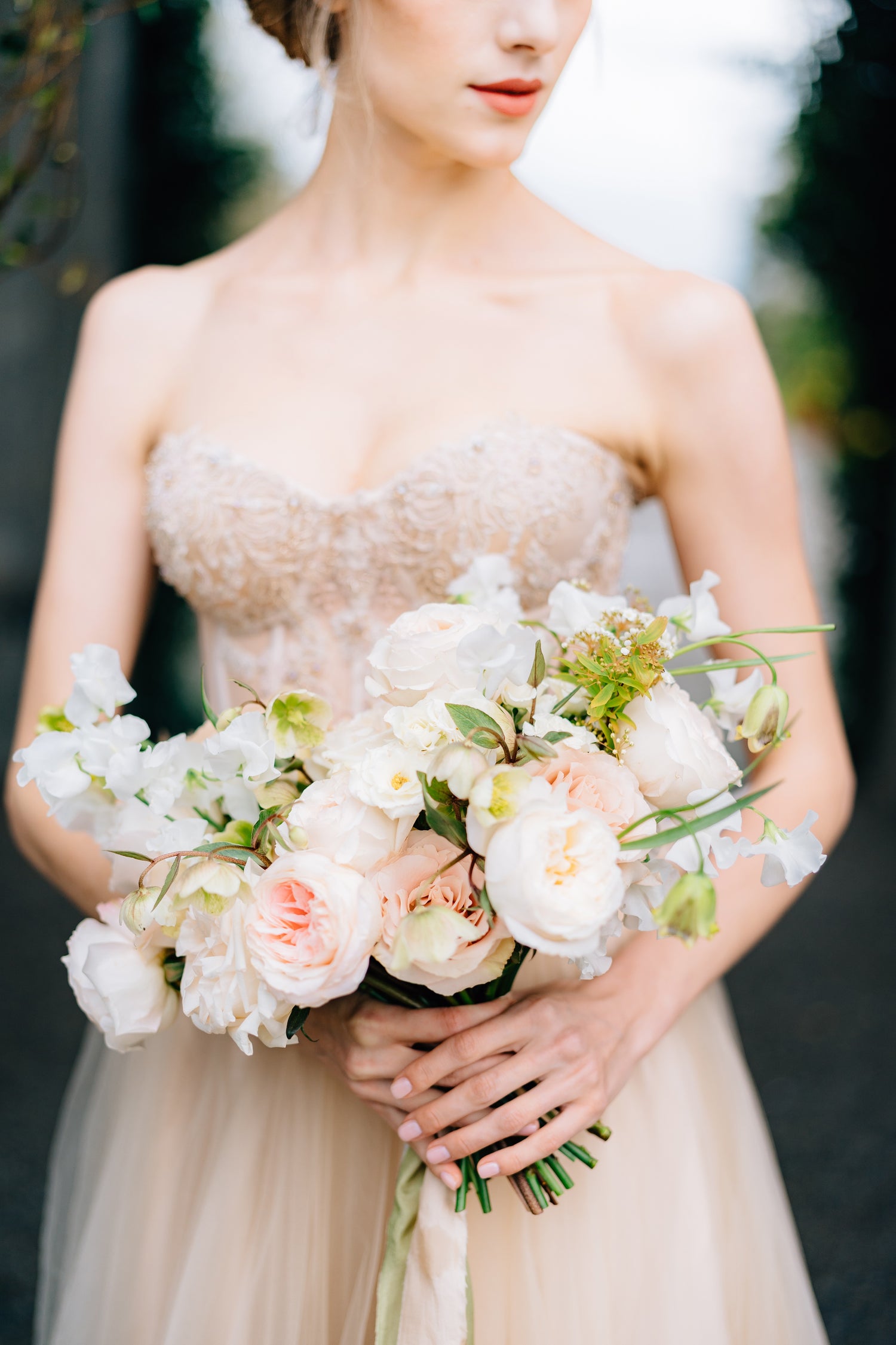Bride holding a bridal  bouquet of flowers wearing a strapless dress.
