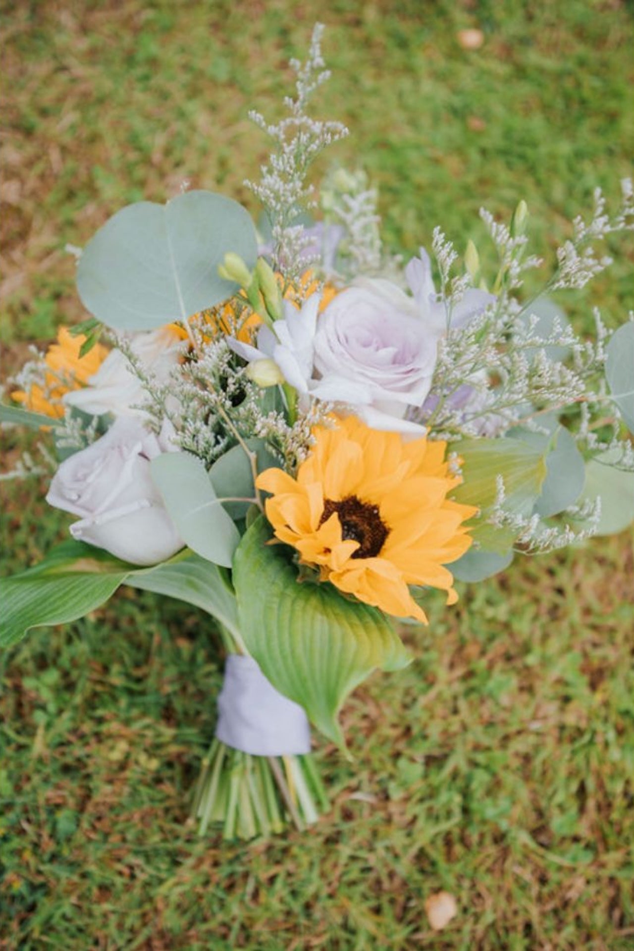 Bouquet with sunflower and roses on a grassy background