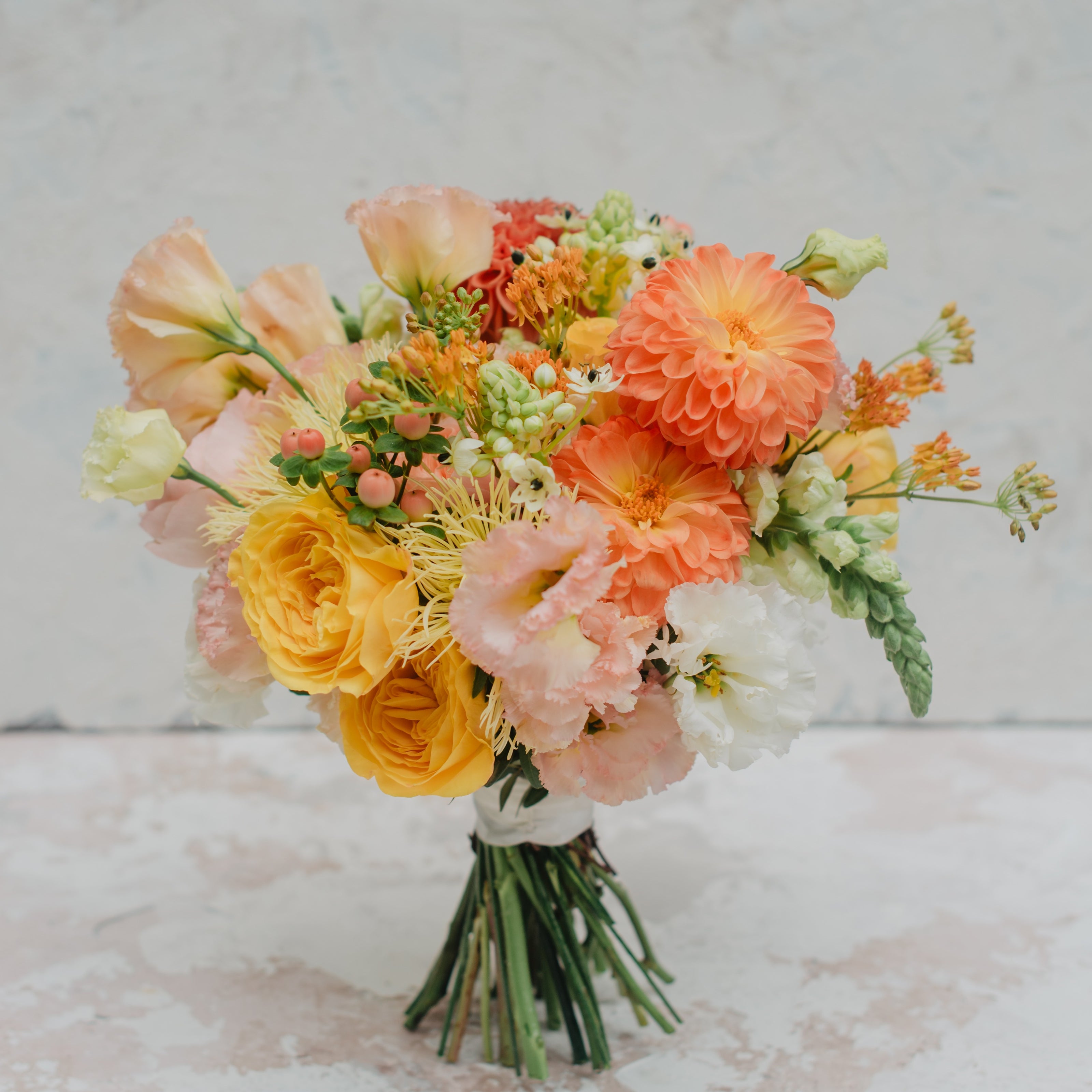 Bouquet of flowers with orange, yellow, and pink colors on a textured surface.