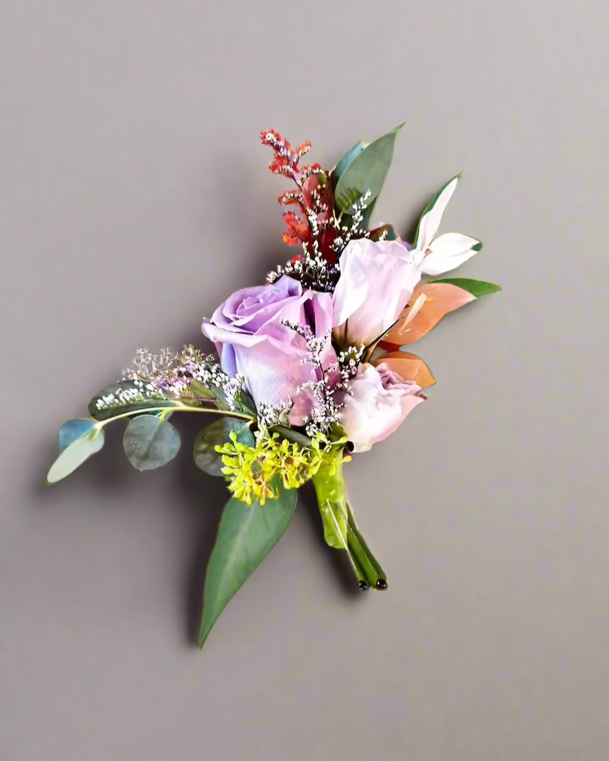 Floral boutonniere with pink and purple flowers on a gray background