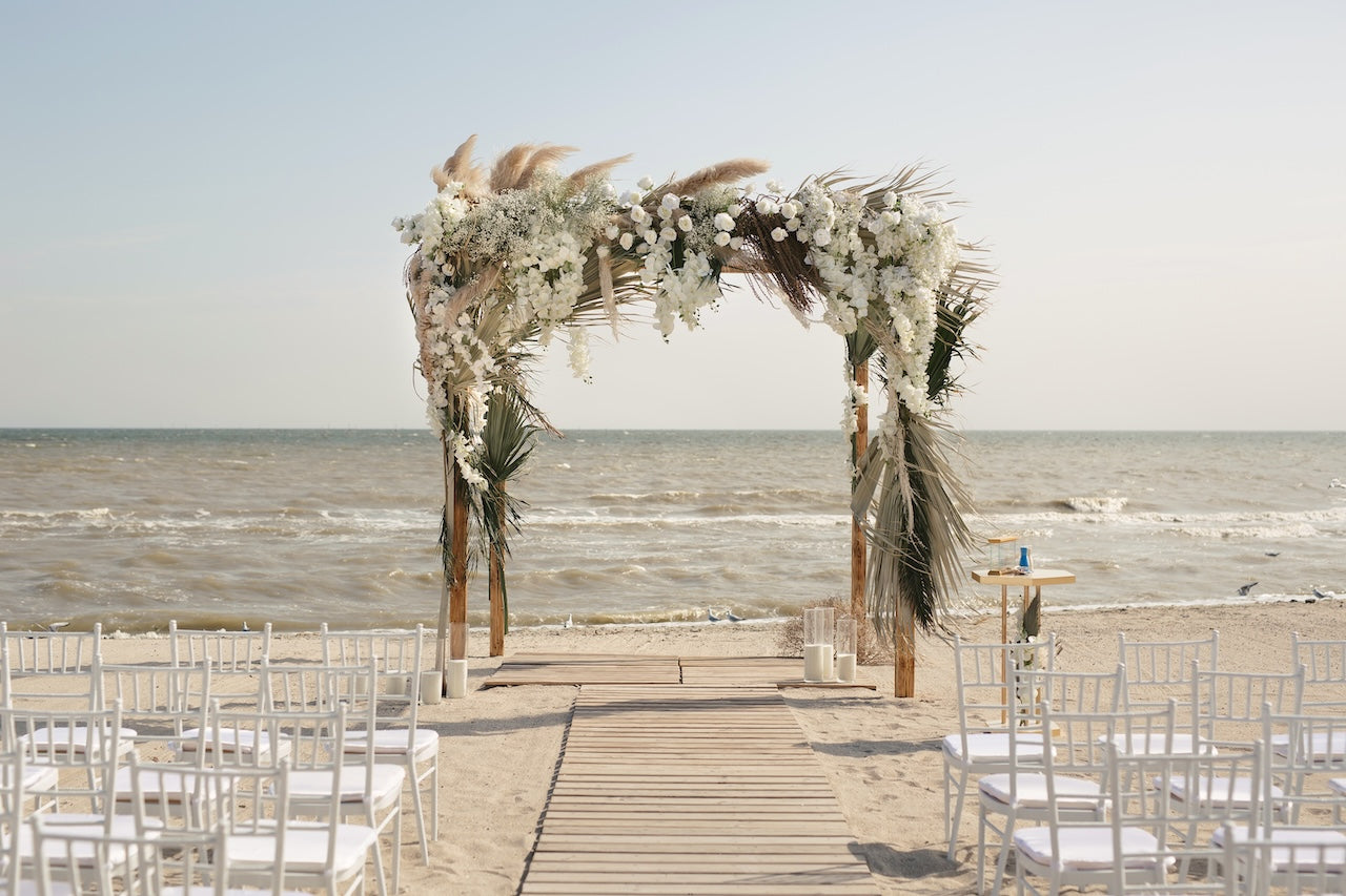 wedding ceremony with floral arch, chairs and tables.