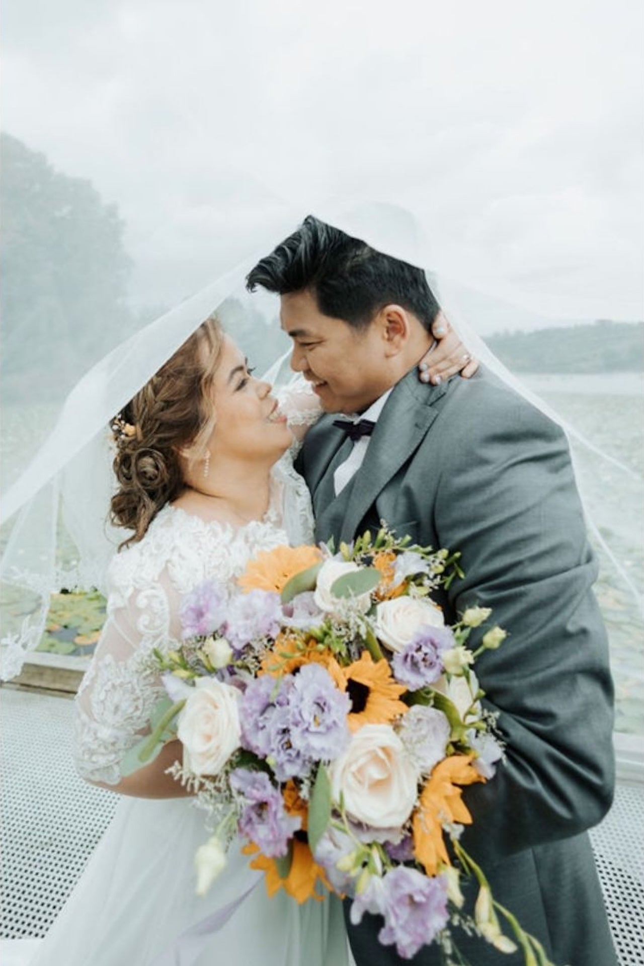 Couple on their wedding day with a bouquet of flowers, standing outdoors.