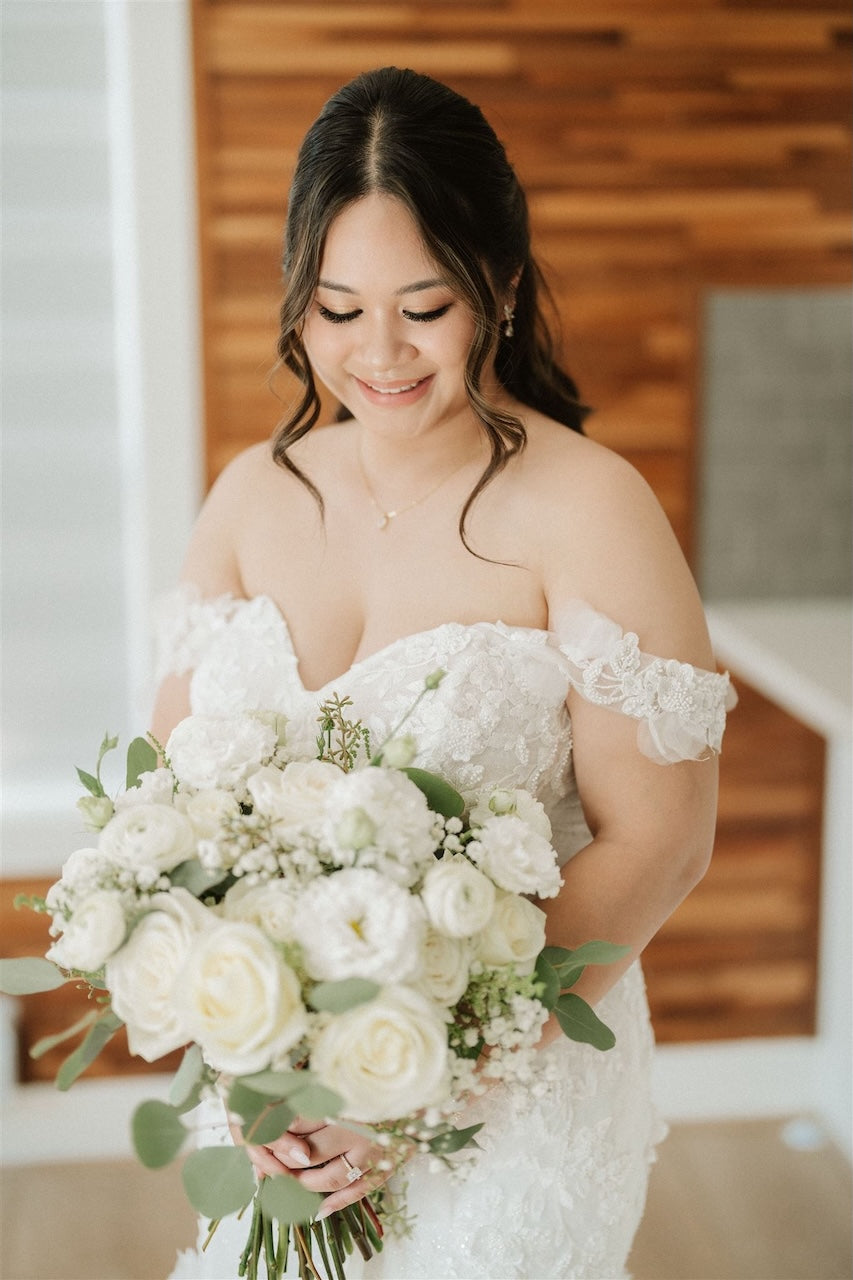 bride holding a white rose, ranunculus, and eucalyptus bridal bouquet made by burst flowers Vancouver.