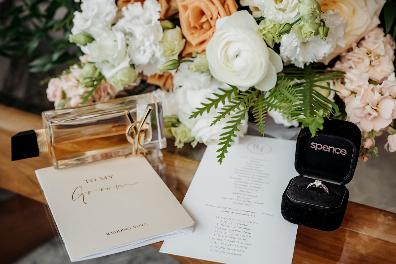 Spence ring box with a ring, flowers, and a card on a wooden surface