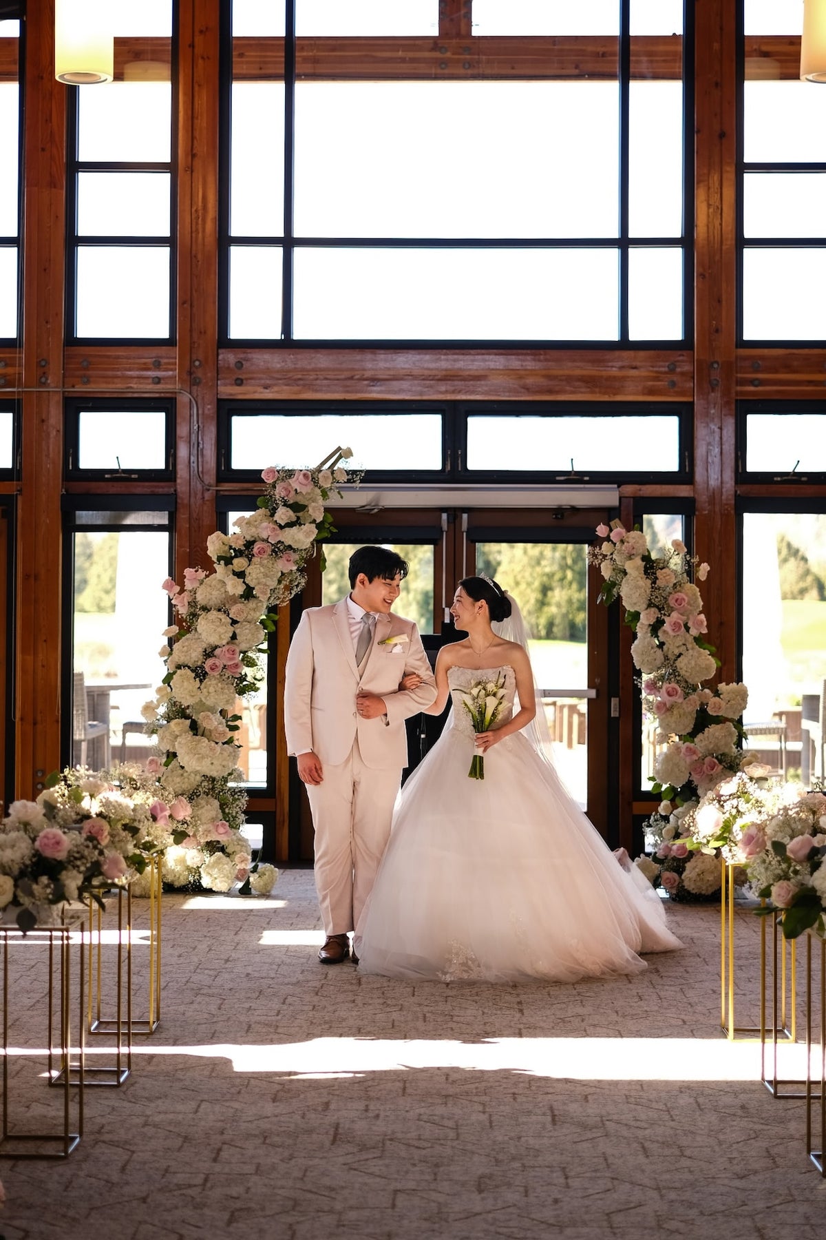 Romantic blush pink and white wedding ceremony arch with floral aisle arrangements at Riverway Clubhouse in Burnaby by Burst Flowers.
