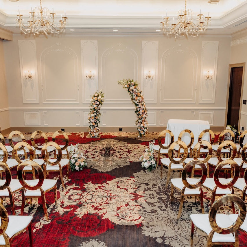Terminal City Club wedding ceremony - event room with gold chairs and floral arch and aisle arrangements on a red carpet 