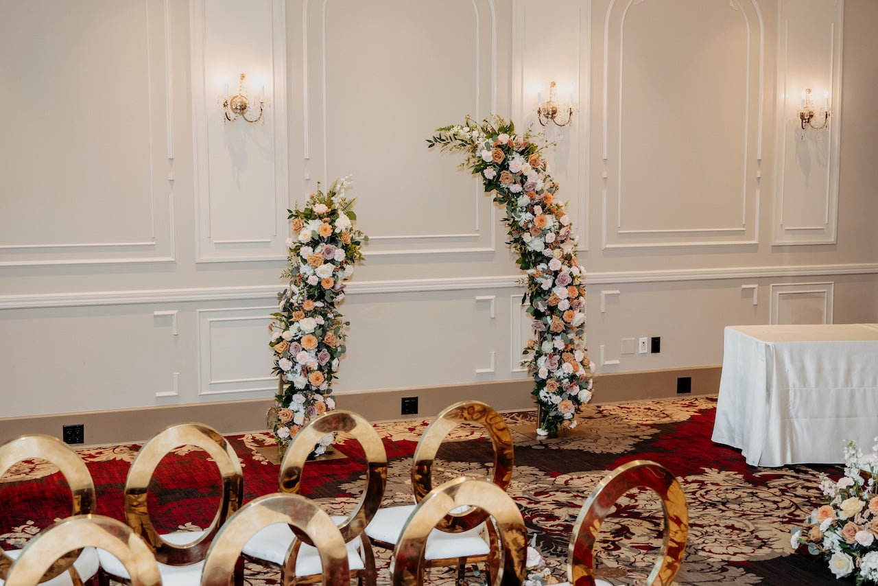 Terminal City Club ceremony - decorated event room with floral arch and aisle arrangements and gold chairs.
