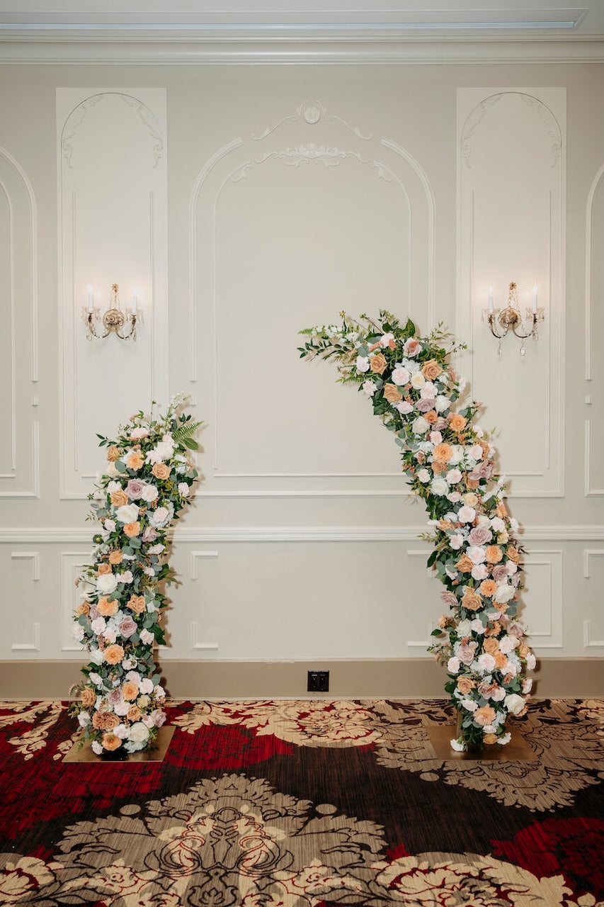 Floral archway setup against a decorative wall with chandeliers for a wedding ceremony at TCC.