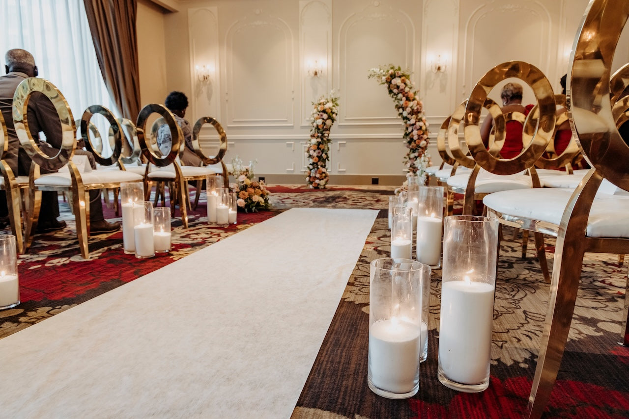 Decorated event space with chairs, candles, and floral arch, aisle arrangements for a wedding ceremony at TCC.