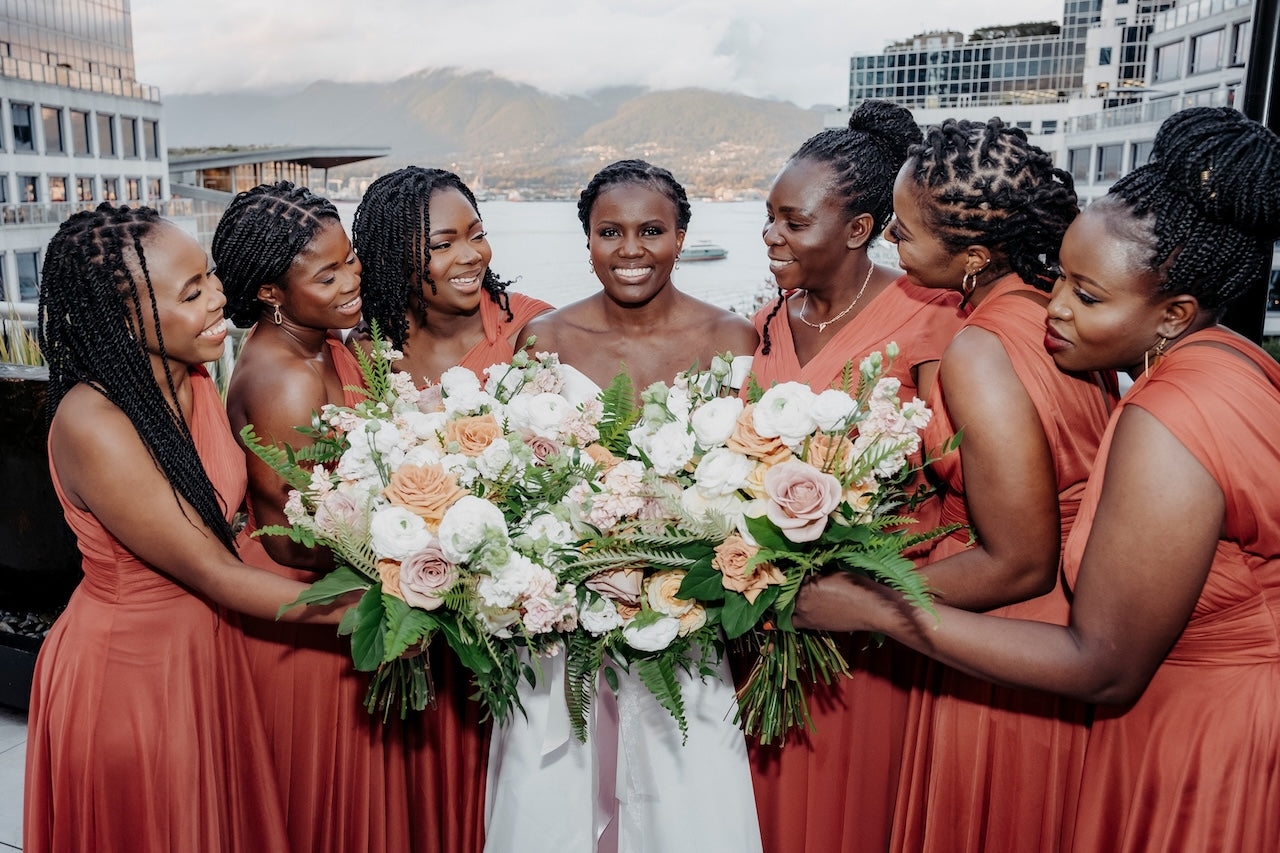 Vancouver Bride and bridesmaids in coral dresses holding floral bouquets with a cityscape in the backgrounder 