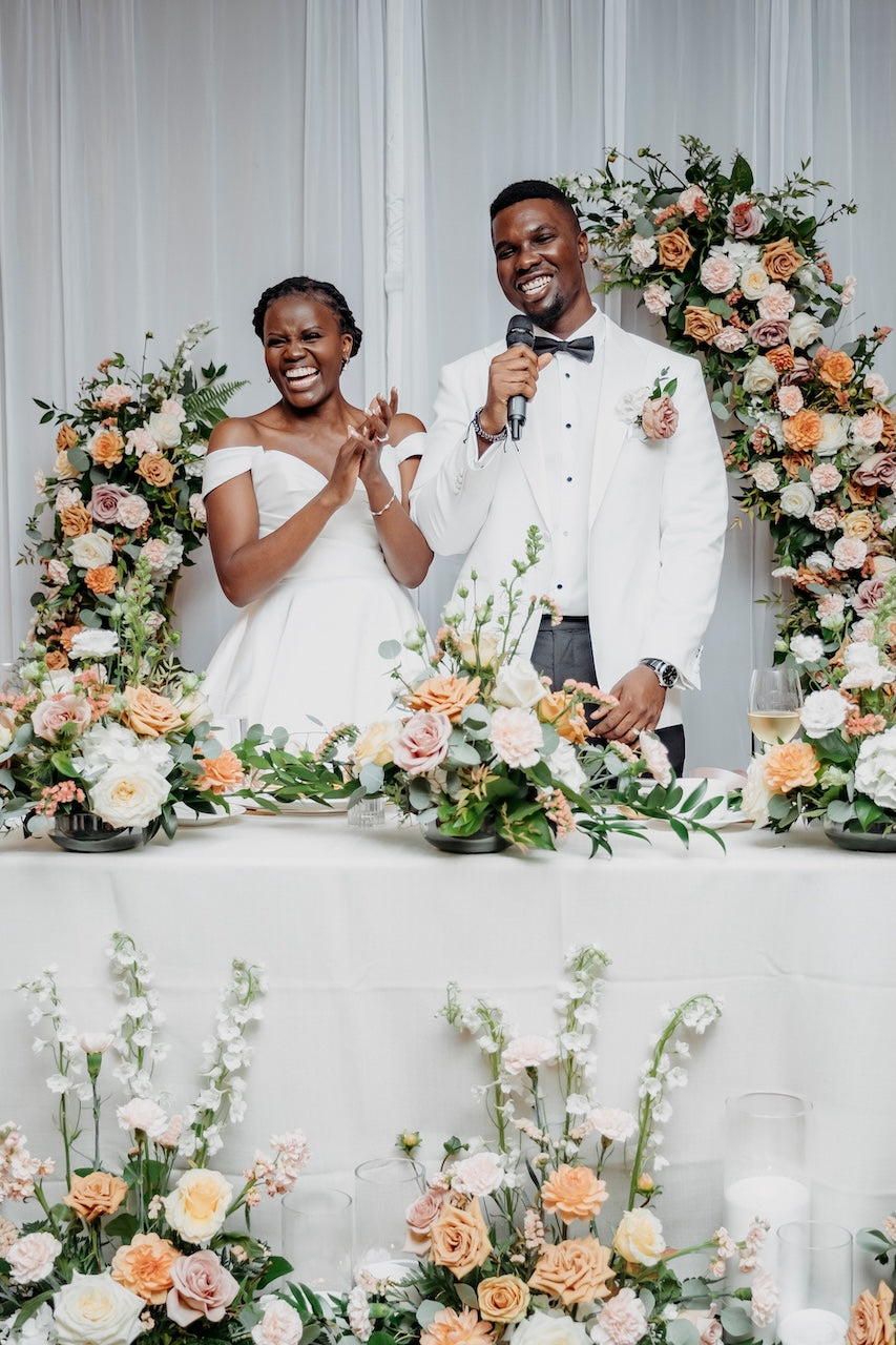 Vancouver Couple standing at a wedding reception with floral decorations and a microphone.