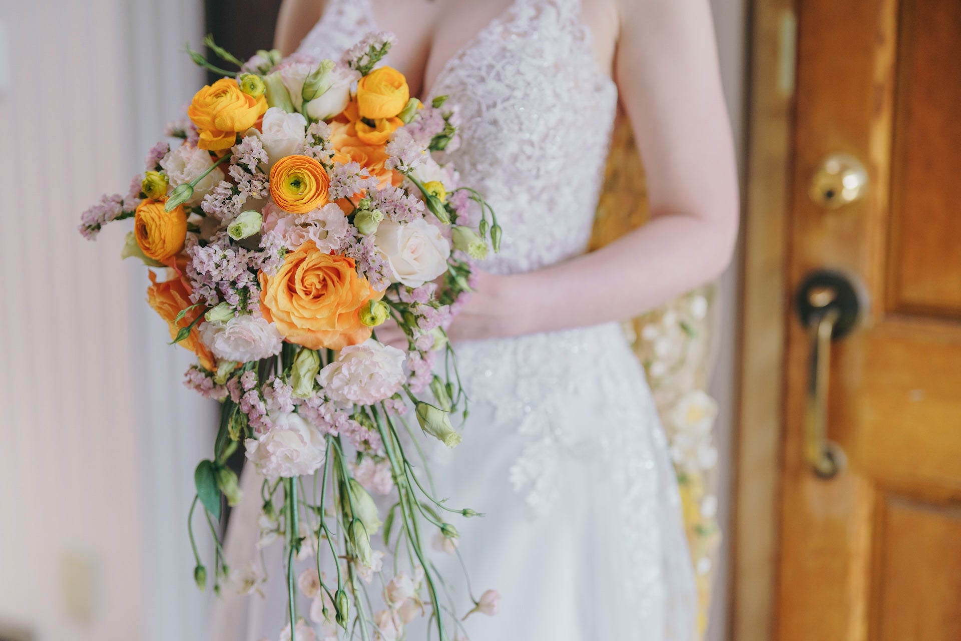 Bride holding a bouquet of flowers in front of a wooden door.