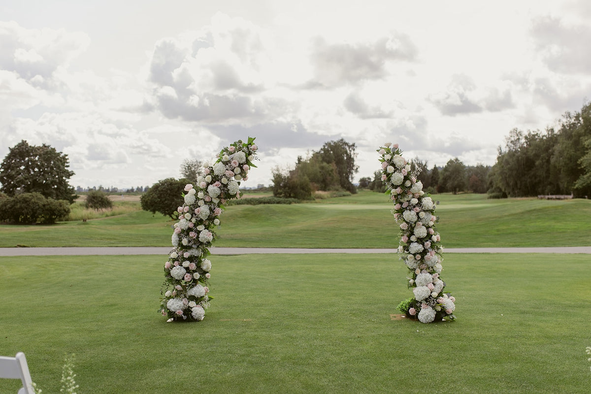 Outdoor wedding ceremony at Swaneset in Pitt Meadows with two floral arch columns.