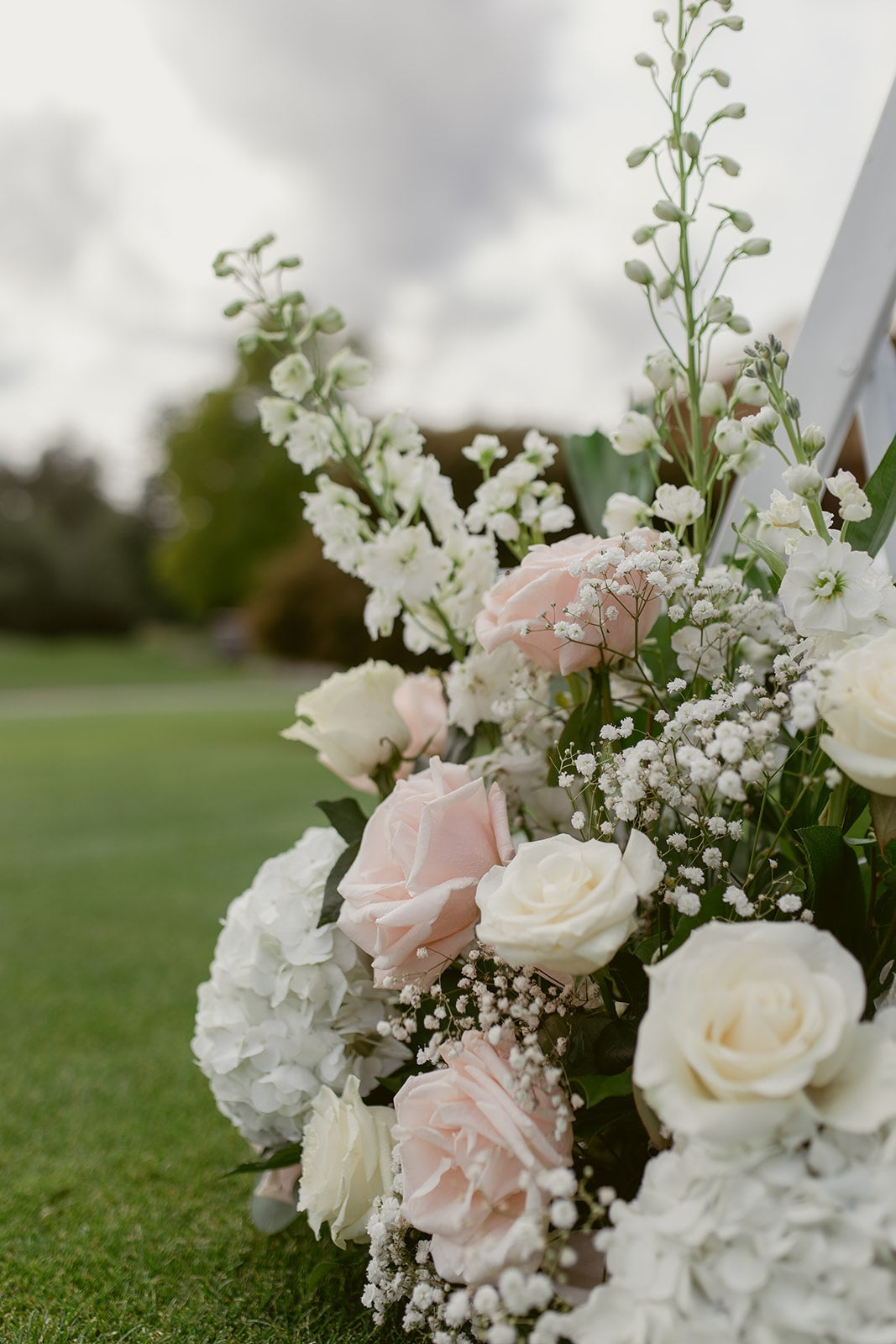 Blush pink roses, white hydrangeas and baby's breath in a romantic Swaneset wedding floral arrangement.