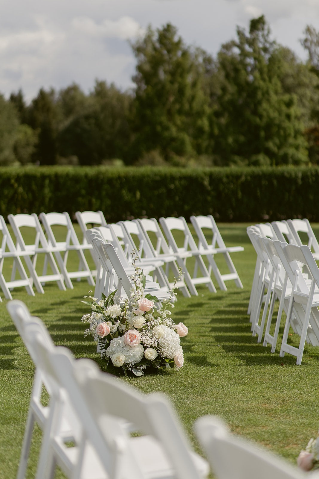 Blush pink roses, white hydrangeas and baby's breath in a romantic Swaneset wedding floral arrangement.