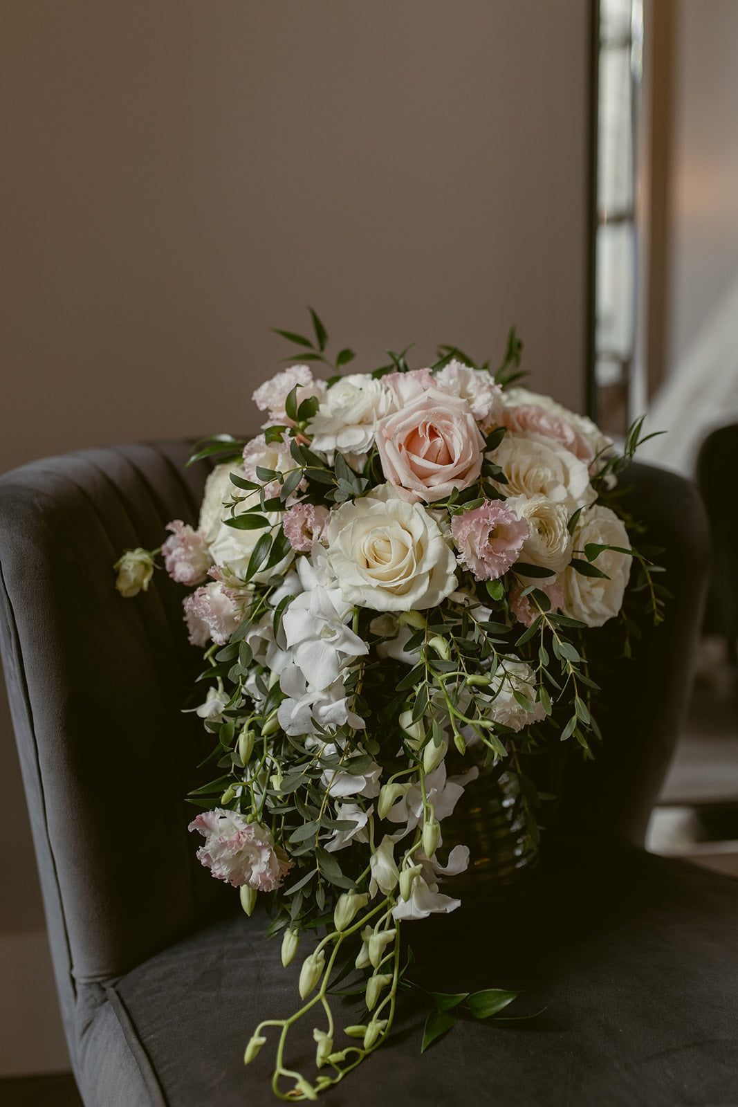 Romantic cascading bridal bouquet with white roses, blush pink flowers, white orchids and greenery by Burst Flowers.