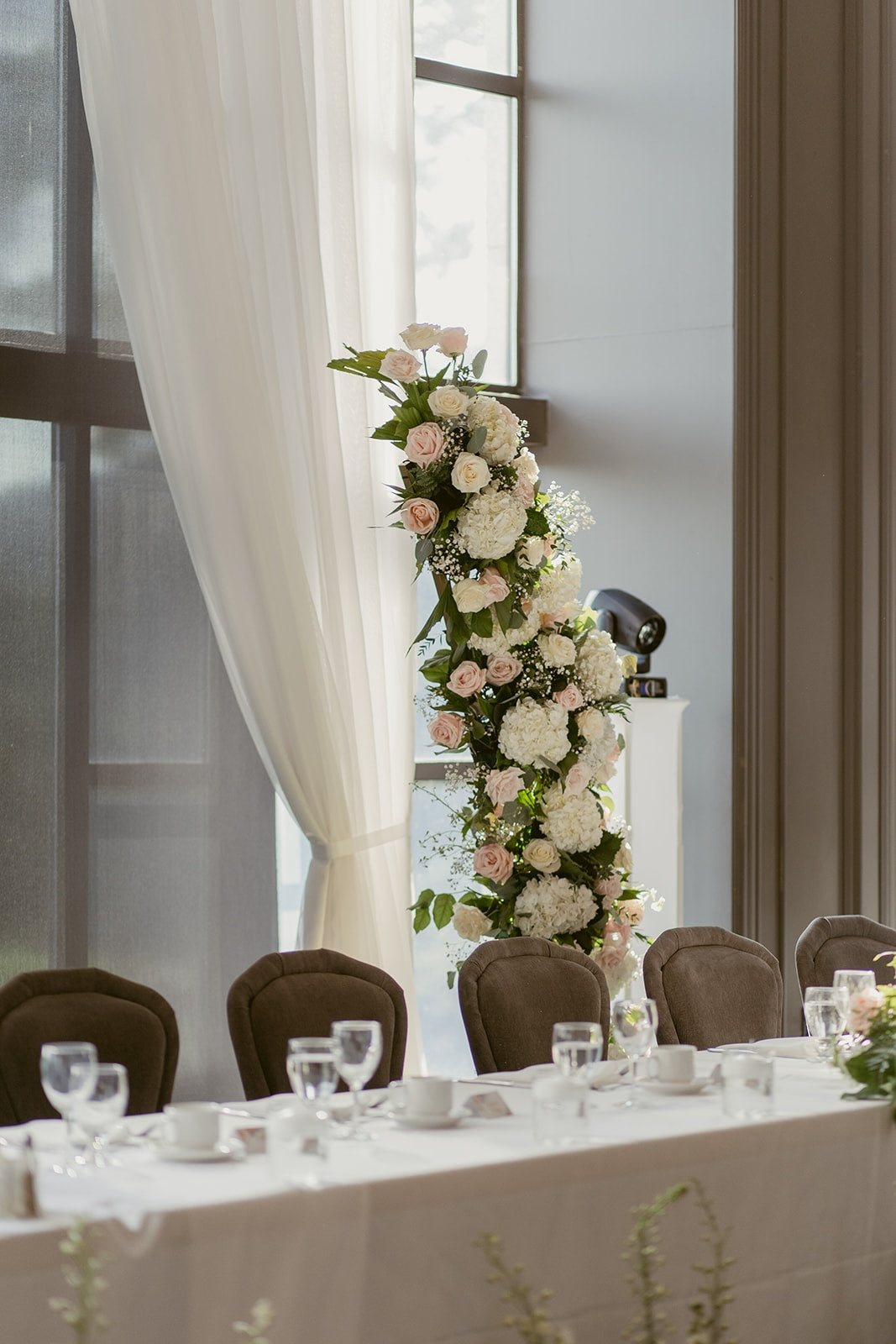 Elegant Swaneset wedding head table with repurposed blush and white ceremony flowers and romantic floral arrangements.
