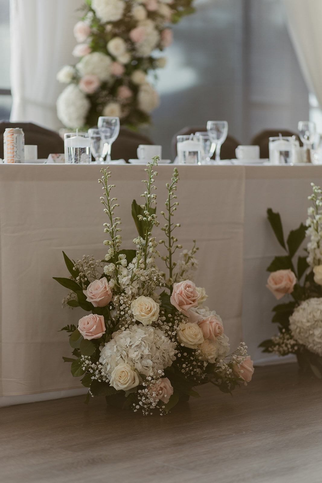 Elegant Swaneset wedding head table with repurposed blush and white ceremony flowers and romantic floral arrangements.