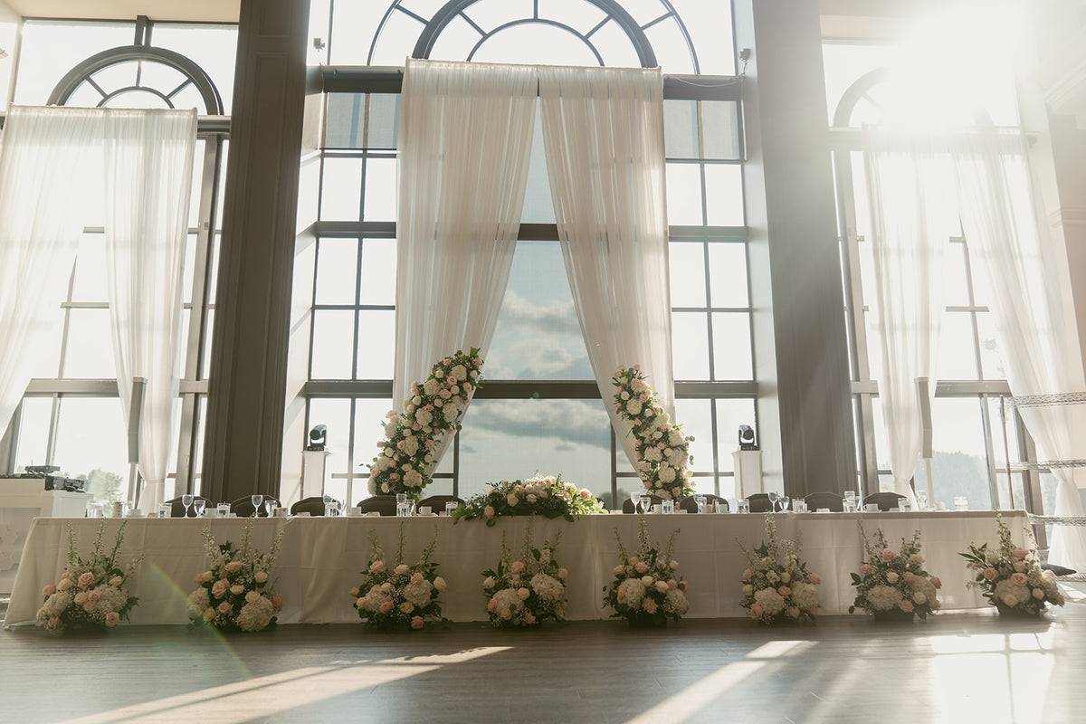 Elegant Swaneset wedding head table with repurposed blush and white ceremony flowers and romantic floral arrangements.