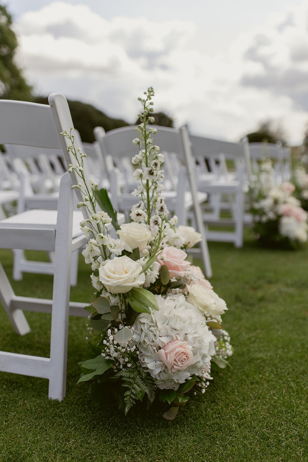Blush pink roses, white hydrangeas and baby's breath in a romantic Swaneset wedding floral arrangement.