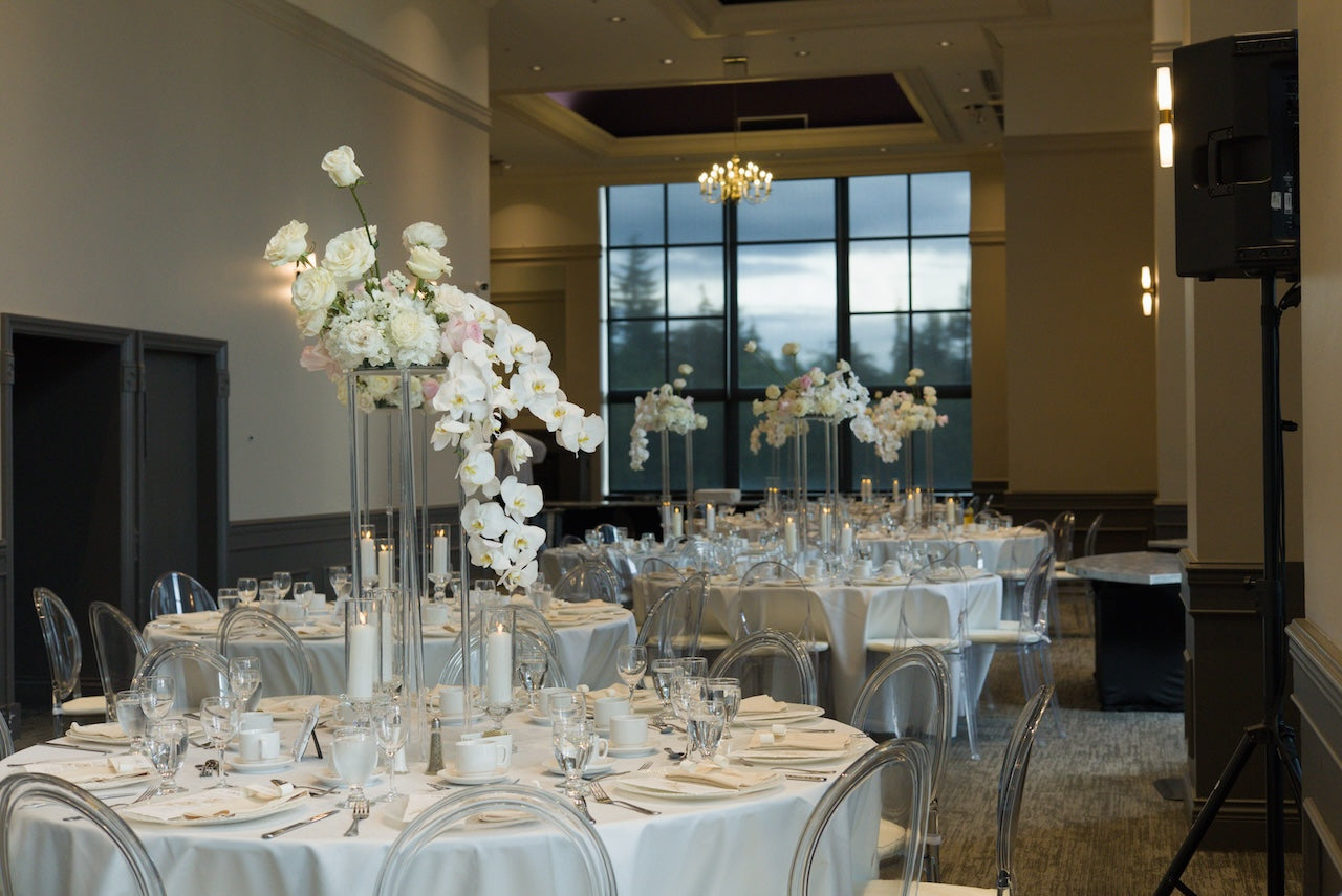 Decorated tables set for a wedding creption, featuring white and light pink floral centerpieces at Swaneset Bay Resort & Country Club grand ball room.