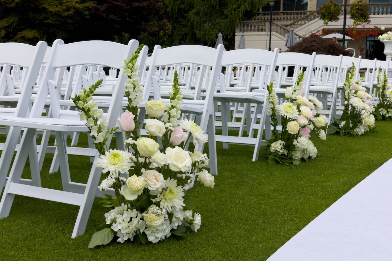 White chairs with aisle floral arrangements at Swaneset Bay Resort & Country Club set up for outdoor wedding.