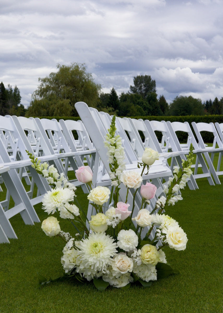 Floral arrangement in front of white chairs at an outdoor wedding at Swaneset Bay Resort & Country Club.
