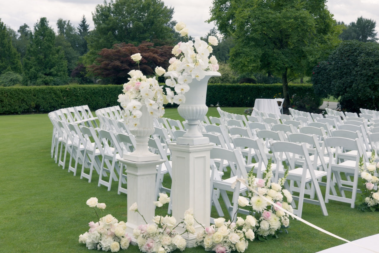 Swaneset Bay Resort & Country Club wedding ceremony setup with white chairs, white and light pink floral arrangements, and a decorative floral arch.