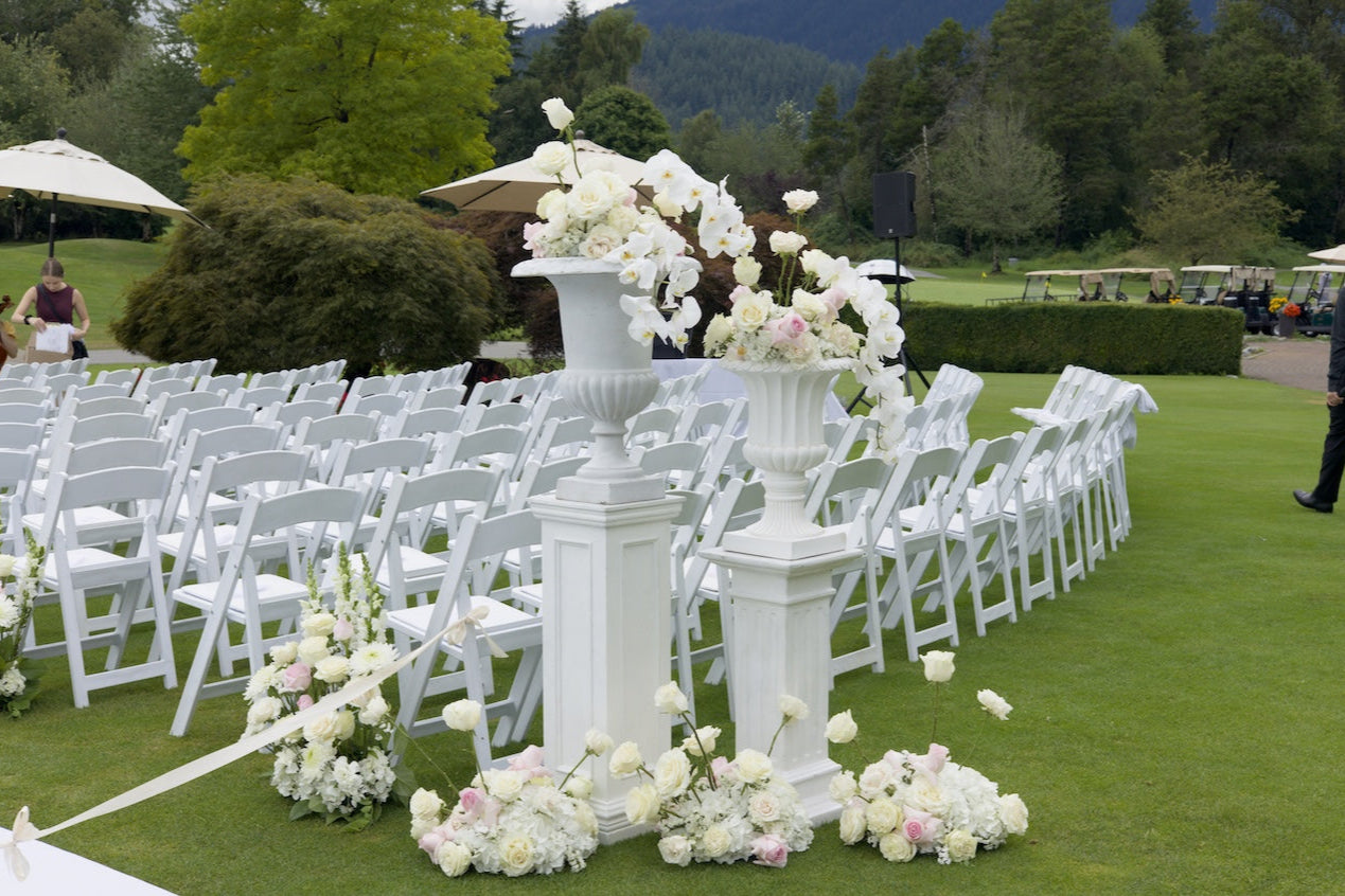 Swaneset Bay Resort & Country Club wedding  setup with white chairs, floral arrangements, and columns on a grassy field.