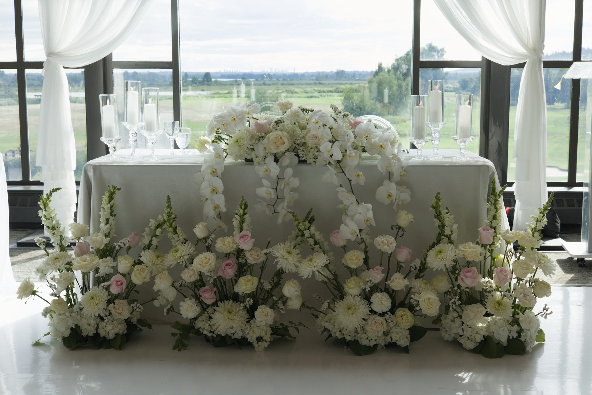 Decorative floral arrangement on a head table with a scenic view outside large windows at Swaneset Bay Resort & Country Club grand ball room.