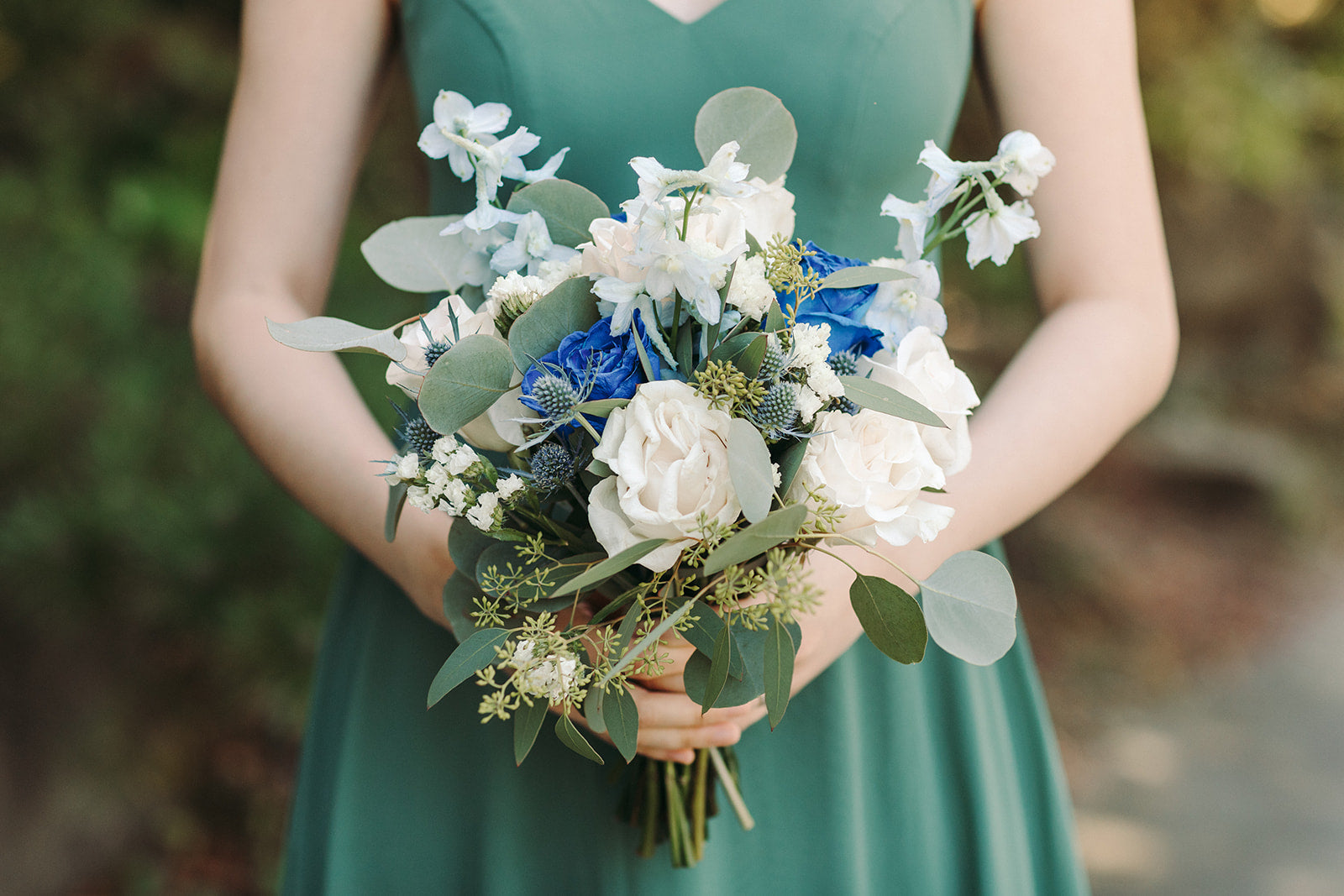 Person holding a bouquet of flowers with a blurred natural background