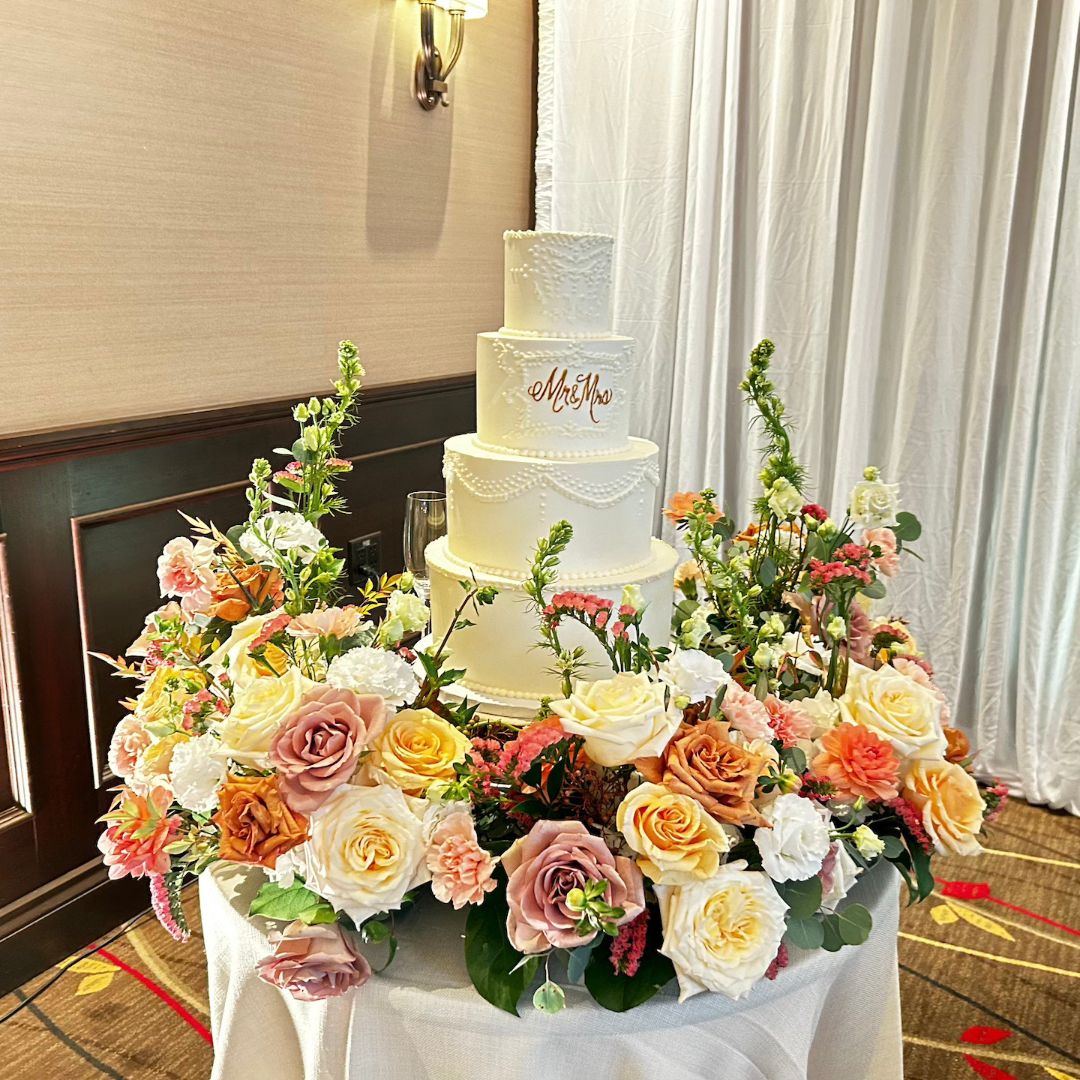 Three-tiered wedding cake with floral decorations on a table.