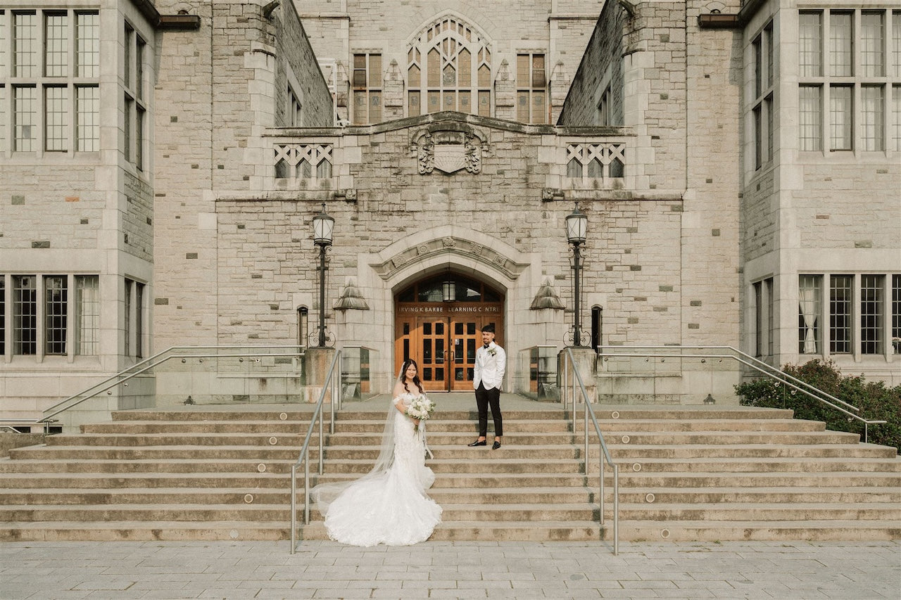 Wedding couple standing on the steps of a large stone church bc.