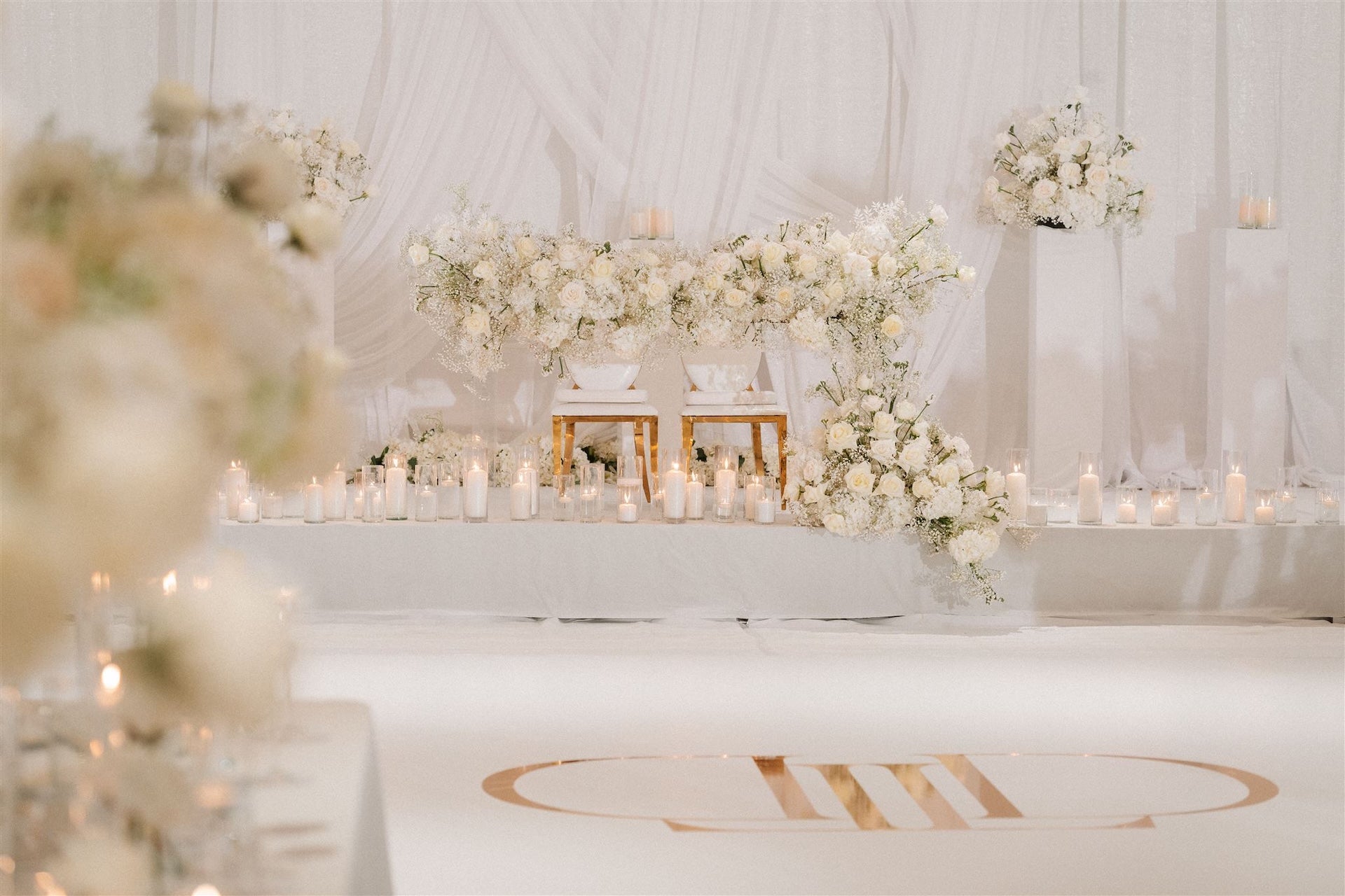 Decorative setup with white flowers and candles on a white surface for a wedding.