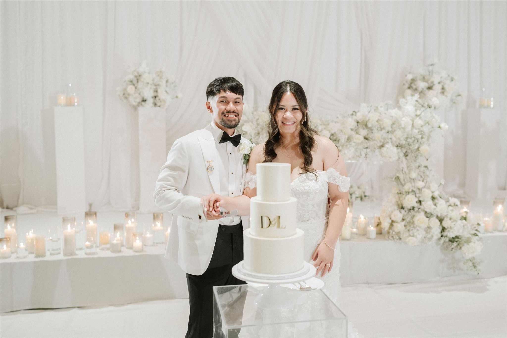 Couple cutting a wedding cake in a decorated room with flowers and candles.