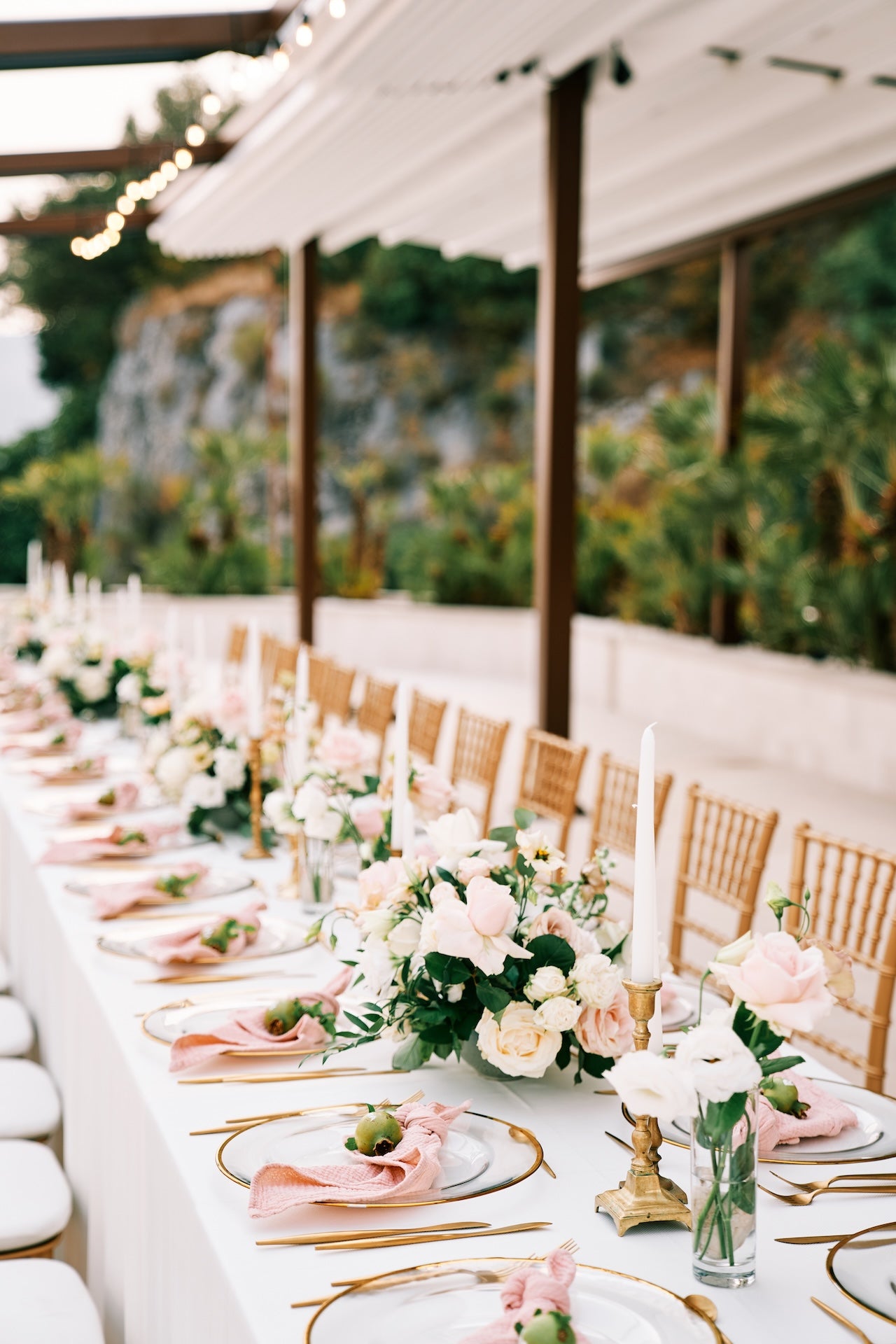 Long table set for a wedding reception with floral centerpieces and white tablecloth.